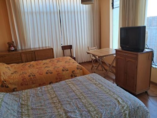 ein Hotelzimmer mit einem Bett und einem TV auf einer Kommode in der Unterkunft san andres, titikaka in Puno