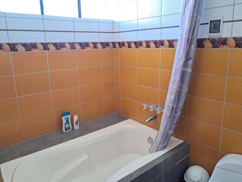 eine Badewanne in einem Badezimmer mit orangefarbenen Fliesen in der Unterkunft san andres, titikaka in Puno