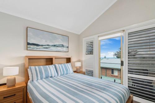 a bedroom with a bed and a large window at Coledale Beach Escape - Modern Comfort by the Sea in Coledale