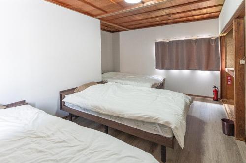 two twin beds in a room with white sheets at ALLEY HOUSE-nachikatsuura in Nachikatsuura