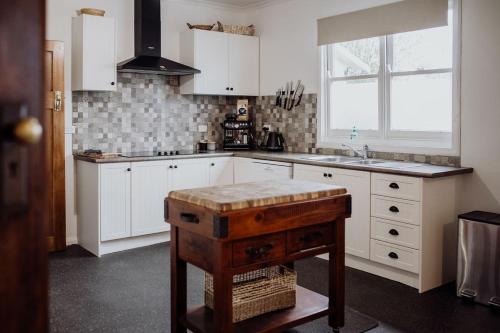 - une cuisine avec des placards blancs, un évier et une table dans l'établissement Cottage on Groom - St Marys Charm and Convenience!, à Saint Marys