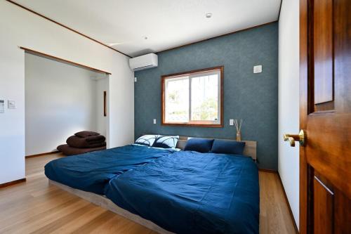 a bedroom with a blue bed and a window at wanpaku99一軒家貸切 in Chosei