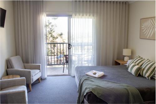 Un dormitorio con una cama, una silla y una ventana en BATHURST GOLDFIELDS MOTEL at 428 CONROD STRAIGHT MOUNT PANORAMA, en Bathurst