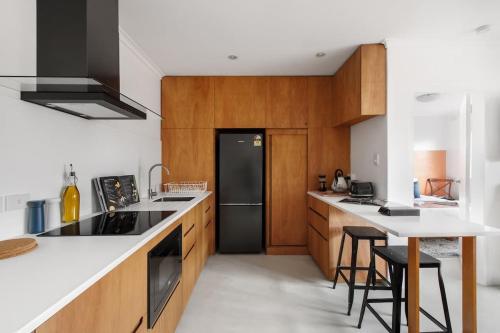 a kitchen with wooden cabinets and a black refrigerator at Stylish 1-Bed Apt with Parking in Heart of Fitzroy in Melbourne
