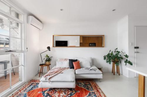 a white living room with a couch and a tv at Stylish 1-Bed Apt with Parking in Heart of Fitzroy in Melbourne