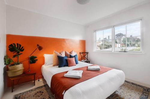 a bedroom with a large bed with an orange headboard at Stylish 1-Bed Apt with Parking in Heart of Fitzroy in Melbourne