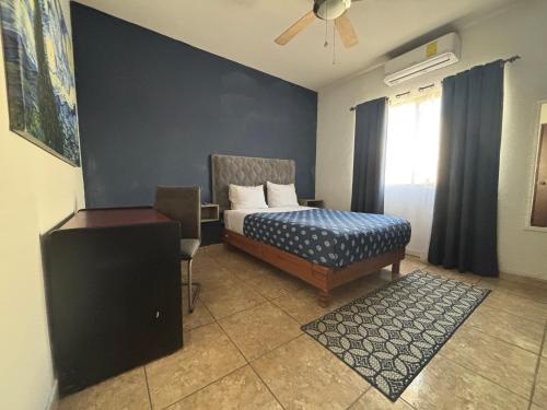 een slaapkamer met een bed, een stoel en een raam bij Habitacion Arboleda in Saltillo