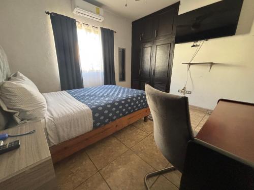 een slaapkamer met een bed, een bureau en een stoel bij Habitacion Arboleda in Saltillo
