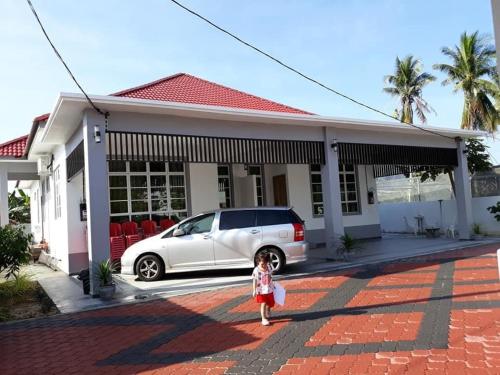 een klein meisje dat voor een huis staat bij Araz Homestsay in Kota Bharu