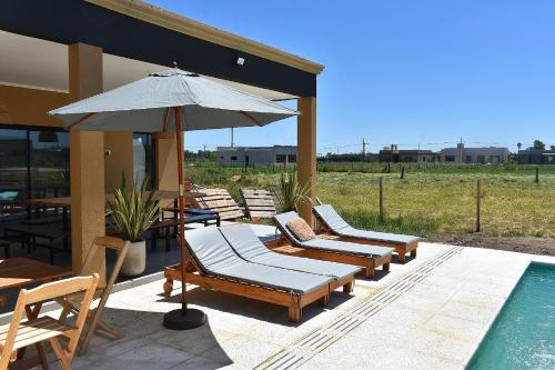 a group of lounge chairs and an umbrella next to a pool at Quinta Natural Glam in San Vicente