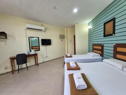 una habitación de hotel con dos camas y un televisor en BCIC Lodge, en Kuantan
