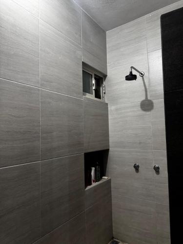 um banheiro com chuveiro e parede de azulejos em The CaSa em Saltillo