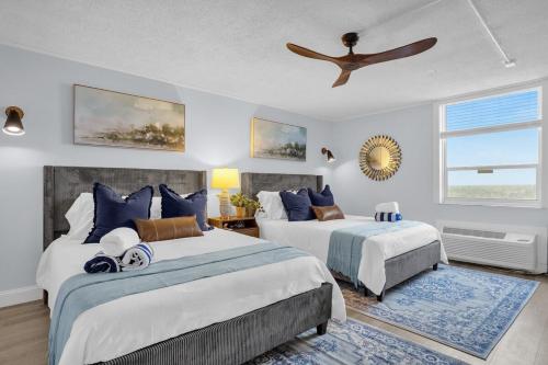 Un dormitorio con dos camas y un ventilador de techo. en Modern Beach Oasis - Sleeps 4 - Pool - Gym - Games, en Daytona Beach