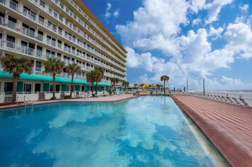 una piscina frente a un hotel y el océano en Modern Beach Oasis - Sleeps 4 - Pool - Gym - Games, en Daytona Beach