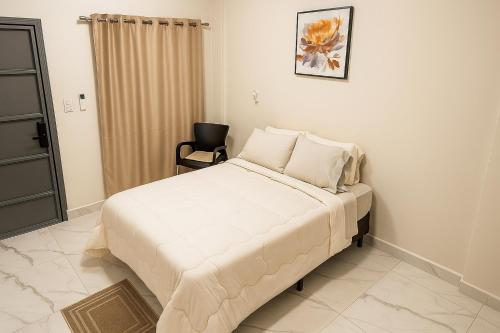 a bedroom with a large bed and a chair at Easy Access Apartment - Ciudad del Este in Ciudad del Este