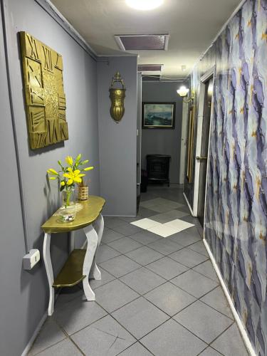 a hallway with a table and flowers on a tile floor at Hotel del valle san Miguel 530 in Melipilla