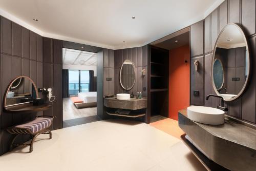 un baño con dos lavabos y dos espejos en Vignette Collection Tiancheng Belmont Hotel Sanya by IHG, en Sanya