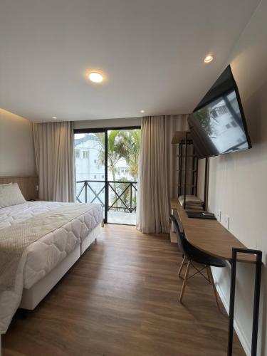 a bedroom with a bed and a desk with a television at Hotel Serra Everest in Nova Friburgo