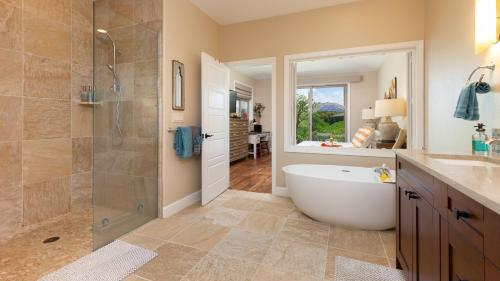 een badkamer met een bad en een glazen douche bij WAHI MALU Comfortable 3BR Single-Level KaMilo Home Near Pool in Waikoloa