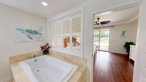 Un baño grande con bañera y ventana. en SERENITY VILLA Serene KaMilo 4BR Home Walk to Pauoa Beach, en Waikoloa