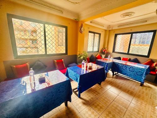 Un restaurante con mesas y sillas azules y ventanas. en Hotel Times, en Katmandú