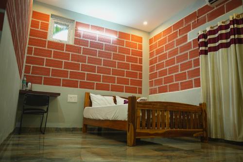 a bedroom with a brick wall with a bed and a chair at The Hills Studio Appartment in Tiruvannāmalai