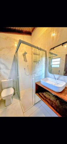 a bathroom with a shower and a sink and a toilet at Pousada Encantos do Rosa in Imbituba