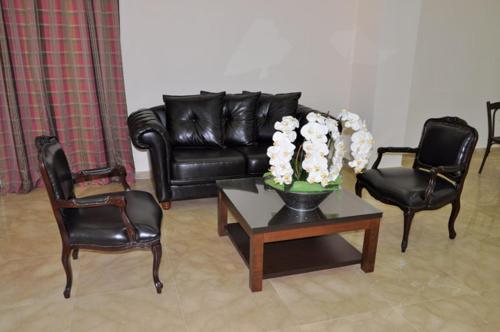 a living room with a black leather couch and chairs at Lagace Hotel in Jounieh