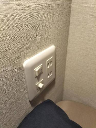 a white outlet on a wall next to a toilet at bnb plus Ueno Park Female only in Tokyo