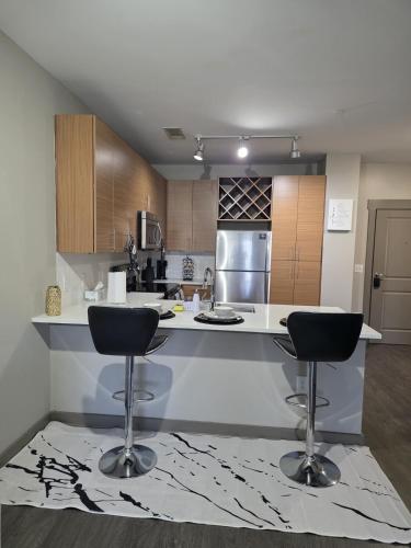a kitchen with two bar stools in front of a counter at Gorgeous Uptown Apartment with Pool in Charlotte