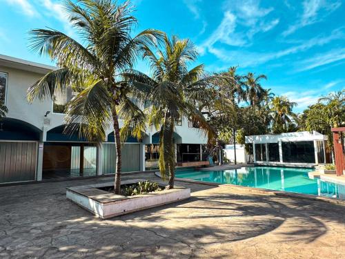 a swimming pool with two palm trees next to a building at Ex Hotel Asturias Centrico in Santa Cruz de la Sierra