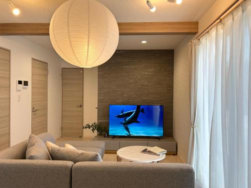 a living room with a couch and a flat screen tv at KADoDE in Kumamoto