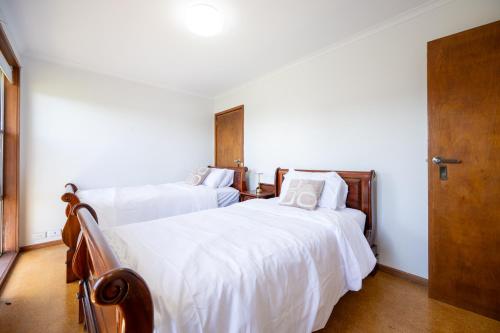 two beds in a bedroom with white sheets at The Valley View Guest House in Melbourne