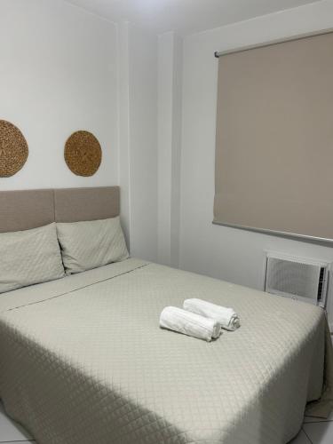 une chambre blanche avec un lit avec deux serviettes dessus dans l'établissement Apartamento em Santos no Gonzaga em frente a praia, à Santos