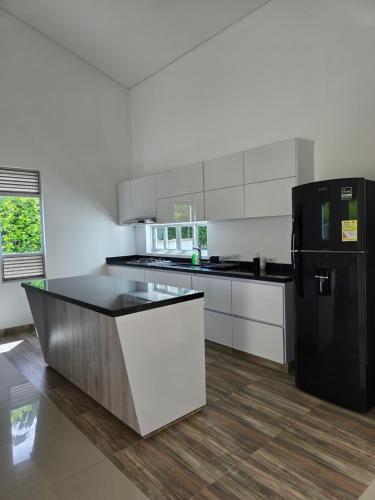 eine Küche mit einem schwarzen Kühlschrank und weißen Schränken in der Unterkunft Casa de Descanso con Piscina y Jardín Ricaurte in Ricaurte