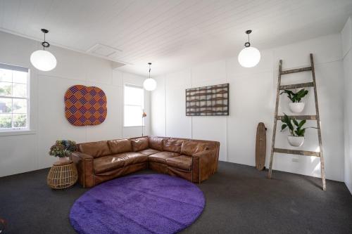 a living room with a brown leather couch and a purple rug at City Apartment - Steps to Cafés, Galleries & Coast in New Plymouth