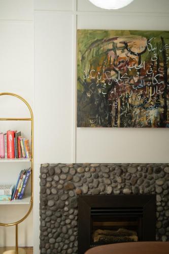 a painting above a fireplace in a living room at City Apartment - Steps to Cafés, Galleries & Coast in New Plymouth