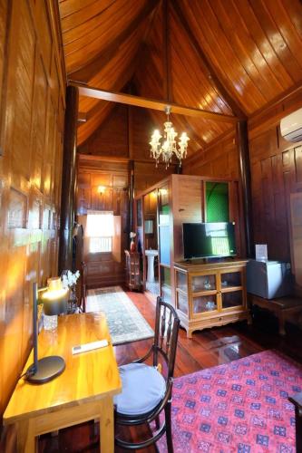 a living room with a table and a television at เรือนไทยพราวพิมาน Proudpiman Thai Heritage House in Ban Bang Toei (1)