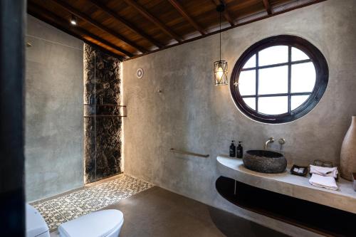 ein Badezimmer mit Waschbecken und Toilette und einem Fenster in der Unterkunft The Mahaloka Uluwatu in Bingin Beach