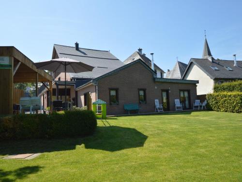 a house with a yard with chairs and an umbrella at Holiday Home in Waimes with Sauna & Bubble Bath in Waimes