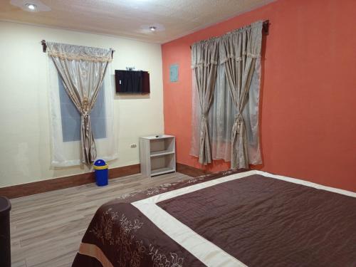 a bedroom with orange walls and a bed and two windows at Casa Cifuentes in La Esperanza