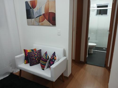 a white bench with pillows on it in a bathroom at Apartamento com piscina e garagem privativa in Londrina