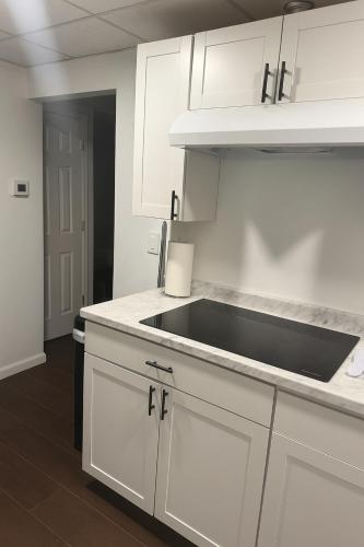 a kitchen with white cabinets and a black sink at Bright & Stylish Guest Suite with Modern Comforts in Selden