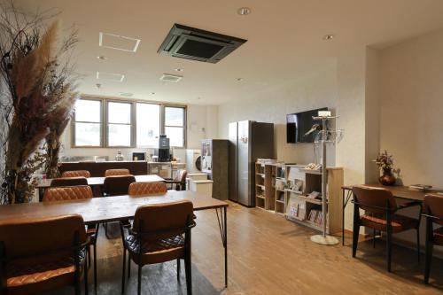 a room with a table and chairs and a living room at Regions Hostel in Yokote