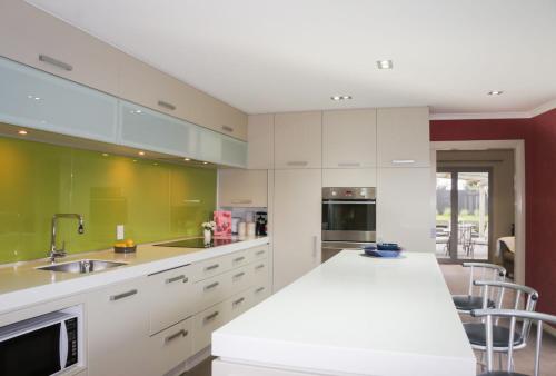 ニュープリマスにあるRelax on Richmond - modern beachside house retreatの白いキャビネットと緑の壁のキッチン