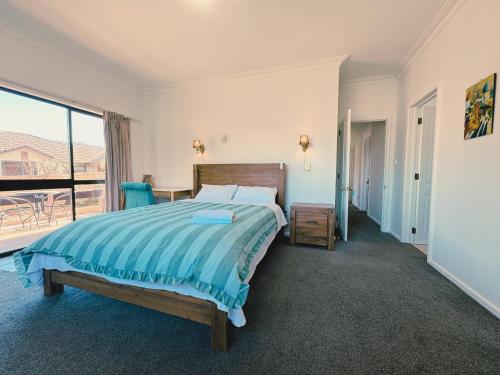 a bedroom with a bed and a large window at Cosy 6BR & 6BA Redwoods Lodge upto 14 People in Rotorua