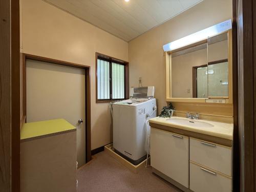 y baño con nevera blanca y lavamanos. en 館山市犬石戸建 自然に囲まれた森のコテージ 6DK 最大18名宿泊可 パーティー BBQ 花火ok, en Tateyama