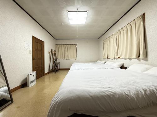 Un dormitorio con una cama blanca grande y una ventana en 館山市犬石戸建 自然に囲まれた森のコテージ 6DK 最大18名宿泊可 パーティー BBQ 花火ok, en Tateyama