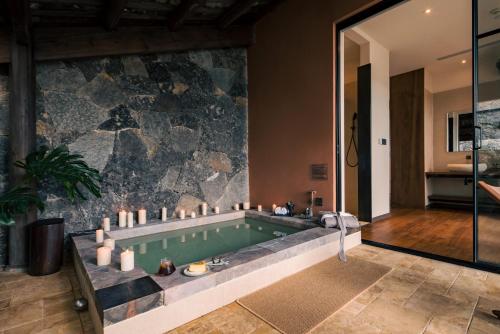 a bathroom with a swimming pool and a stone wall at GengYun Hot Spring Resort Hotel in Niujie