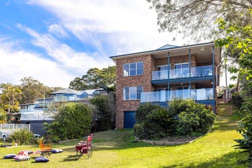 a brick house with a yard with people sitting on the lawn at Zahirs Retreat in North Arm Cove